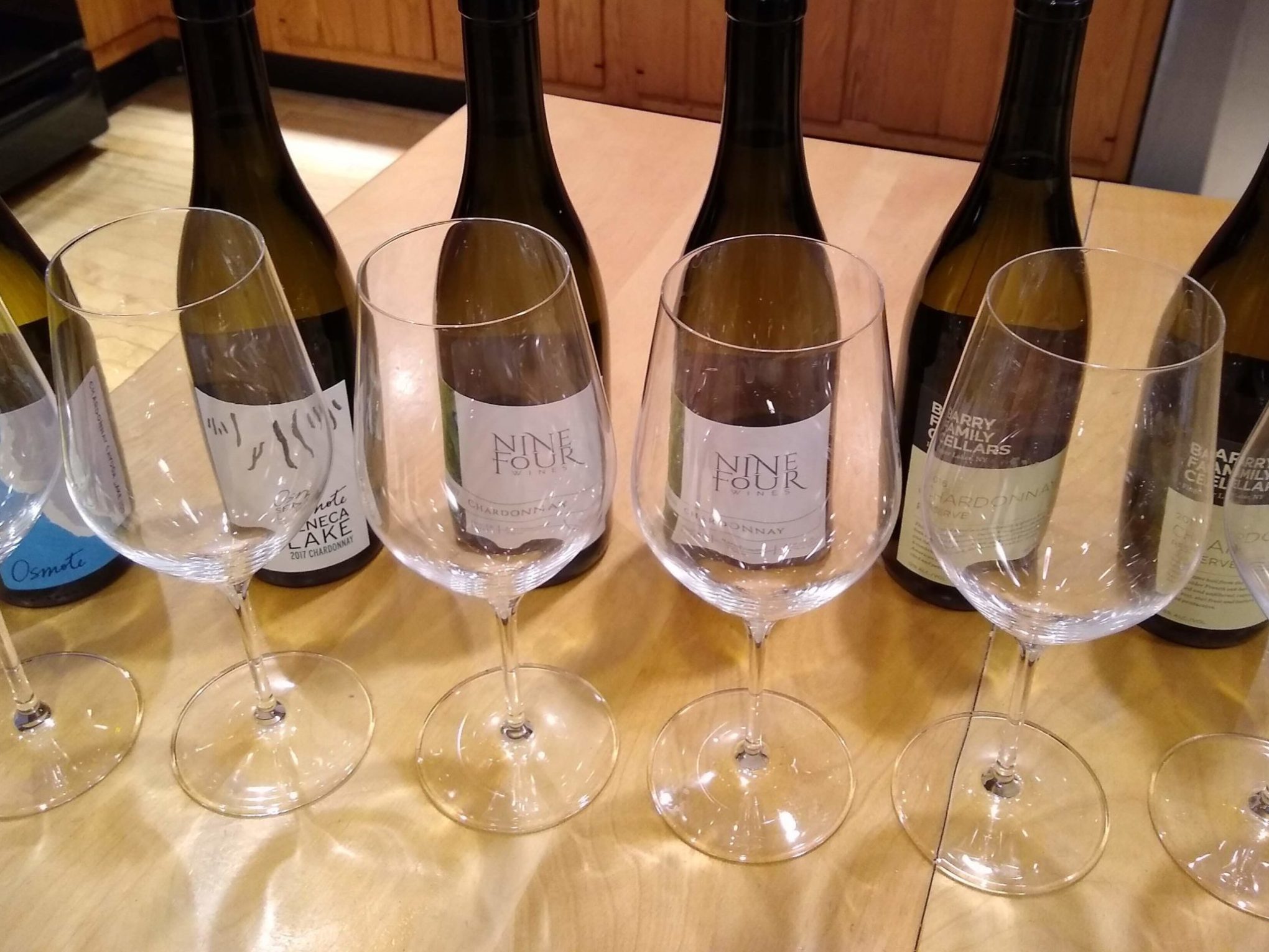 an empty bottle on a table with wine glasses