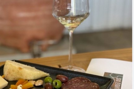 Wine glass with charcuterie platter on wooden table.