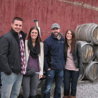 a group of people posing for a photo in front of a barrel