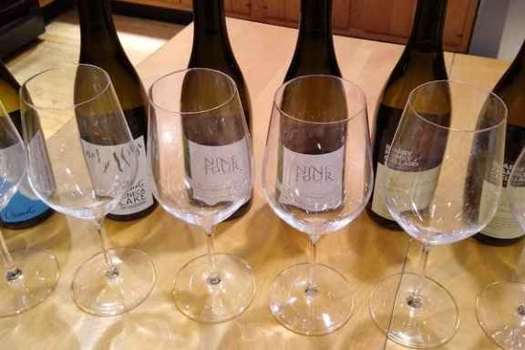 an empty bottle sitting on top of a table filled with wine glasses