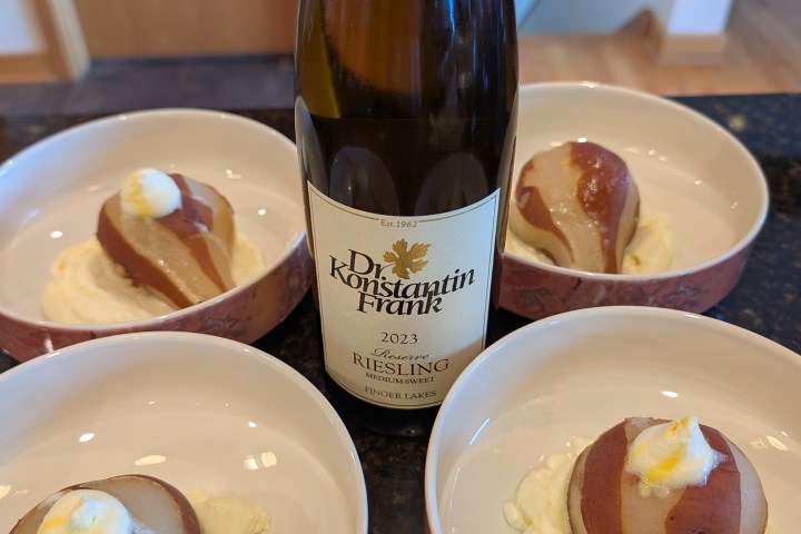 Wine bottle with poached pears in bowls, each on a bed of cream.