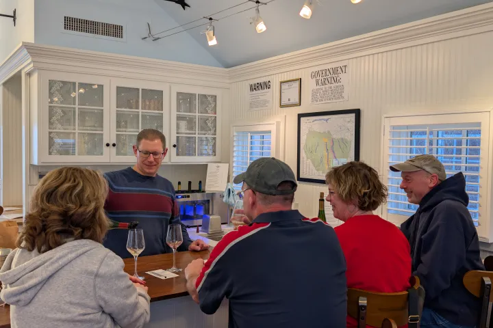 People sitting at a bar counter in a cozy room with maps on the wall.